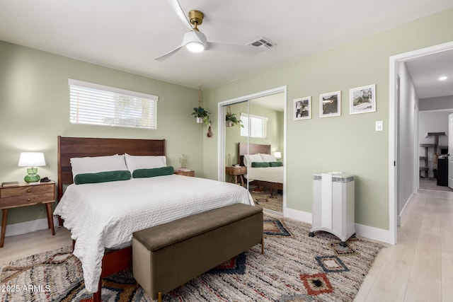 bedroom with multiple windows, ceiling fan, light wood-type flooring, and a closet