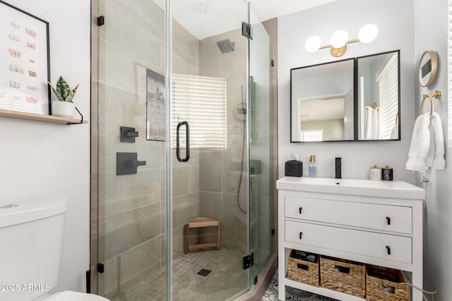 bathroom featuring vanity, a shower with door, and toilet