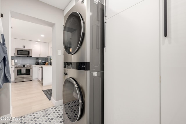 laundry room with sink, light hardwood / wood-style flooring, and stacked washer and clothes dryer