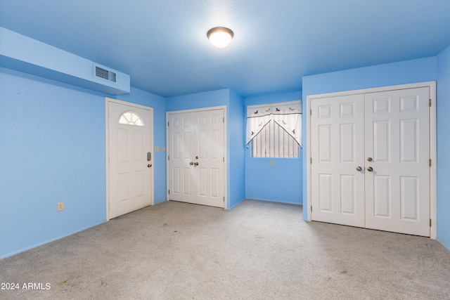 unfurnished bedroom with multiple closets, a textured ceiling, and carpet flooring