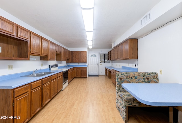 kitchen featuring white range, light hardwood / wood-style floors, and sink