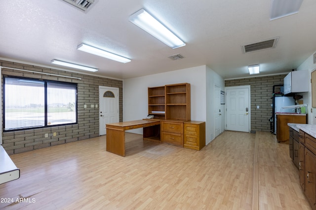 office featuring brick wall, a textured ceiling, and light wood-type flooring