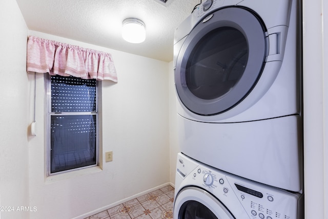 clothes washing area with light tile floors, stacked washing maching and dryer, and a textured ceiling