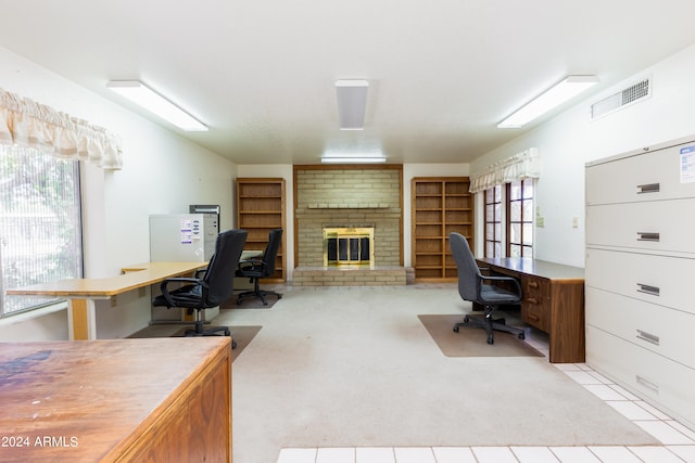 carpeted office featuring a wealth of natural light, brick wall, and a brick fireplace