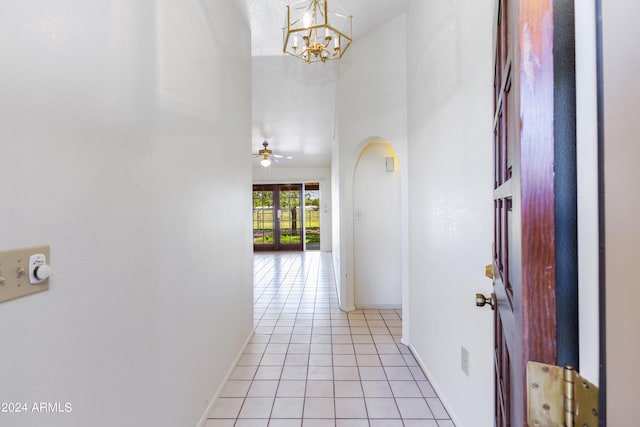 hallway featuring light tile flooring, a chandelier, and a high ceiling