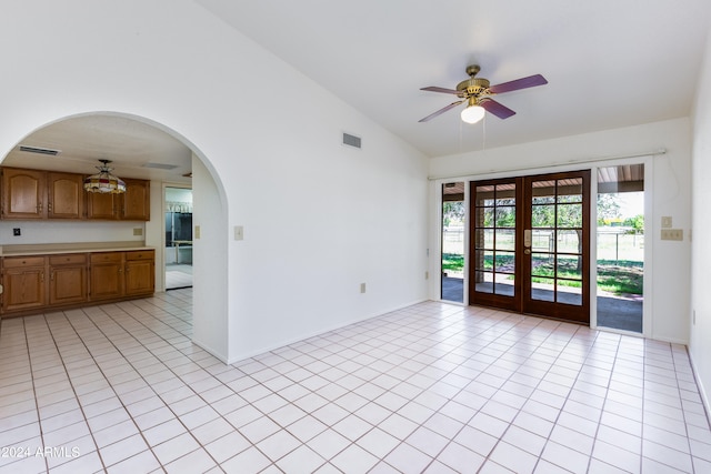 tiled empty room with vaulted ceiling, french doors, and ceiling fan