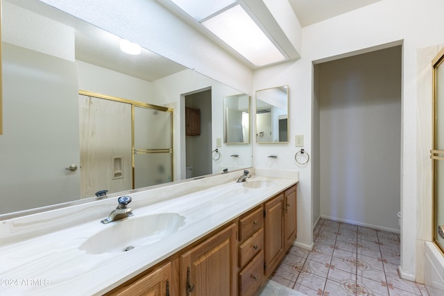 full bathroom with toilet, vanity with extensive cabinet space, shower / bath combination with glass door, tile floors, and dual sinks