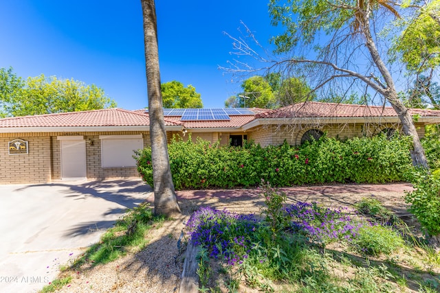 single story home featuring solar panels and a garage