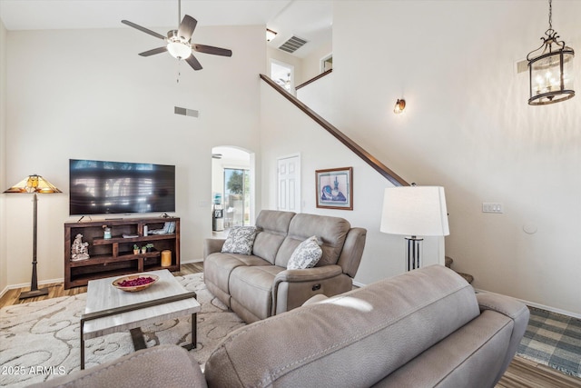 living room featuring ceiling fan with notable chandelier, arched walkways, visible vents, and wood finished floors