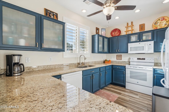 kitchen with glass insert cabinets, white appliances, and a sink