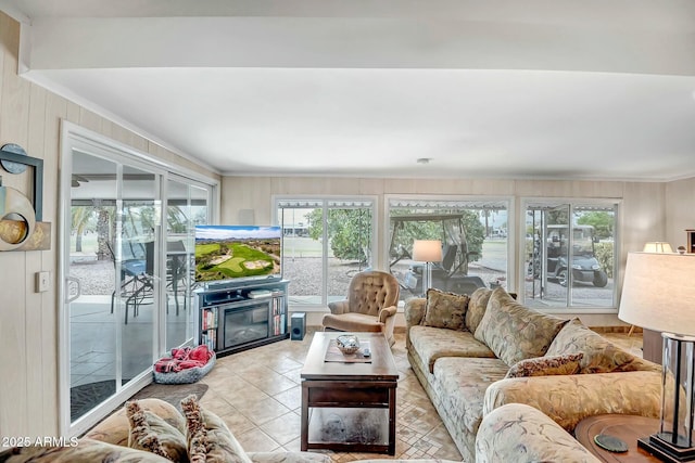 living area featuring a glass covered fireplace, crown molding, and light tile patterned floors