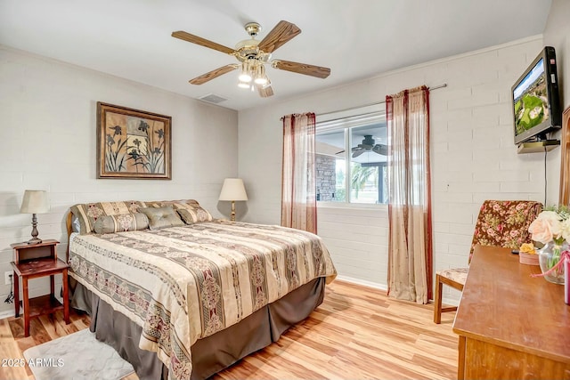 bedroom featuring visible vents, ceiling fan, light wood-style flooring, and brick wall