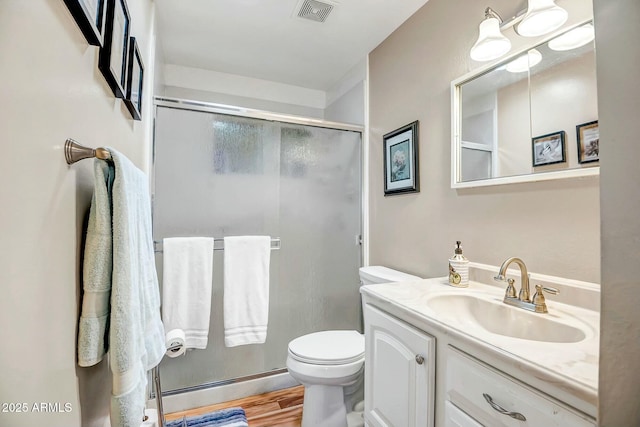 full bath with visible vents, toilet, a shower stall, vanity, and wood finished floors