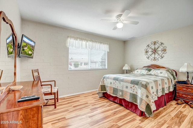 bedroom featuring ceiling fan, brick wall, and wood finished floors