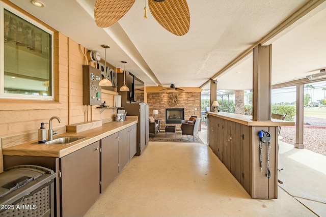 view of patio with an outdoor living space with a fireplace, a sink, and area for grilling