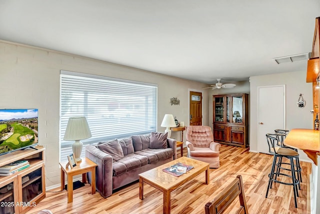 living area with a ceiling fan, visible vents, and light wood-style flooring