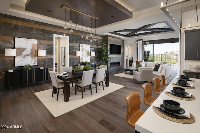 dining room featuring a tiled fireplace, a notable chandelier, coffered ceiling, and dark wood-style floors