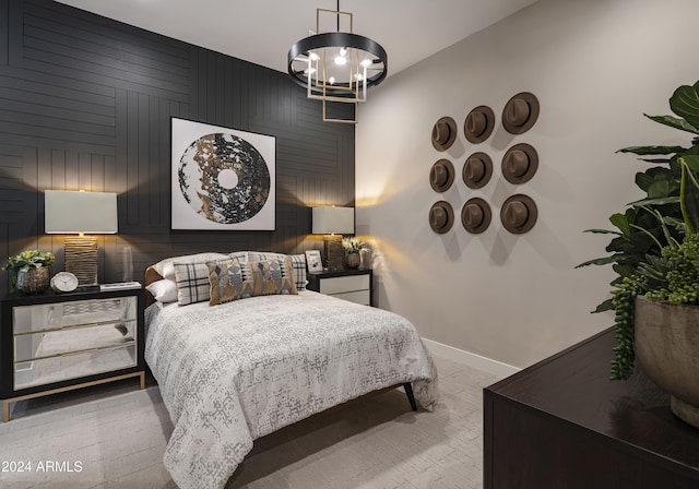 bedroom featuring an accent wall, wood walls, baseboards, and a notable chandelier