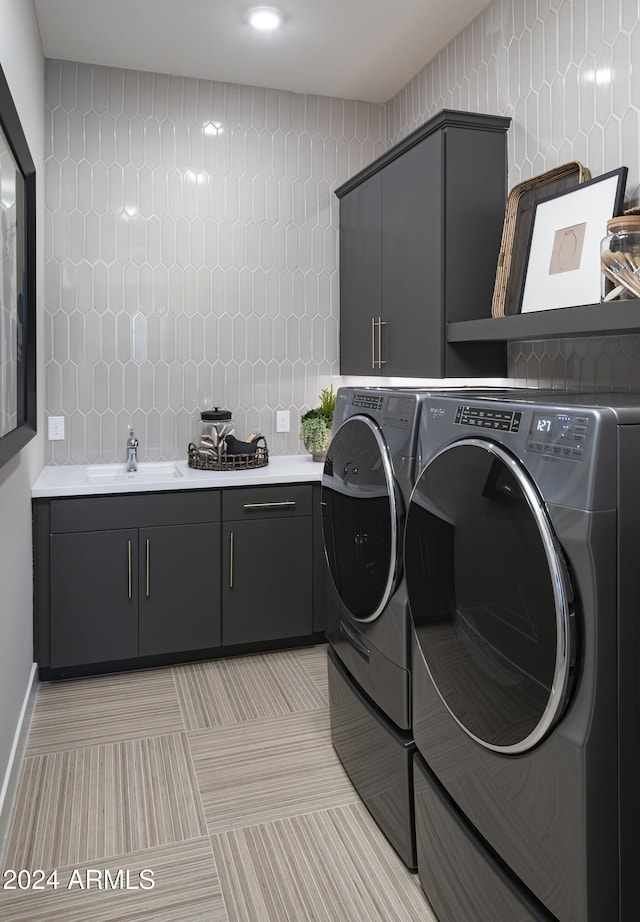 washroom featuring baseboards, independent washer and dryer, a sink, and cabinet space