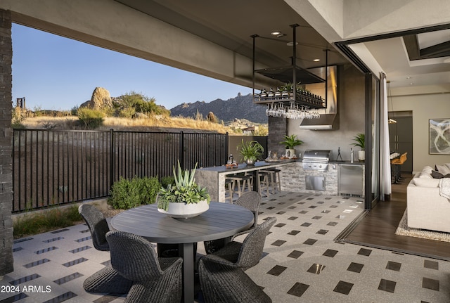 view of patio / terrace with an outdoor kitchen, grilling area, fence, a mountain view, and outdoor dining area