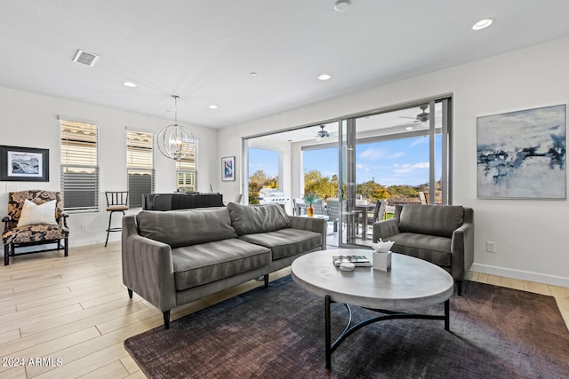 living room with hardwood / wood-style floors and ceiling fan with notable chandelier