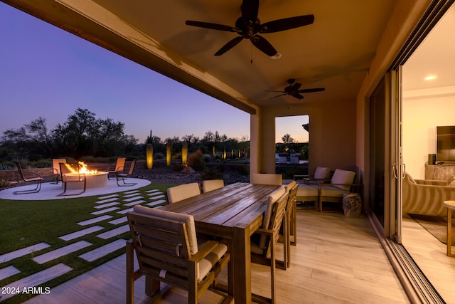 patio terrace at dusk with an outdoor living space with a fire pit and ceiling fan