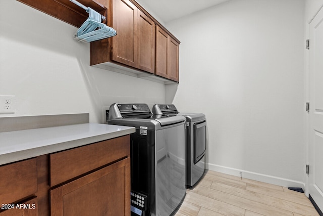 laundry area featuring separate washer and dryer, light hardwood / wood-style floors, and cabinets