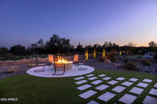 patio terrace at dusk with a fire pit and a lawn