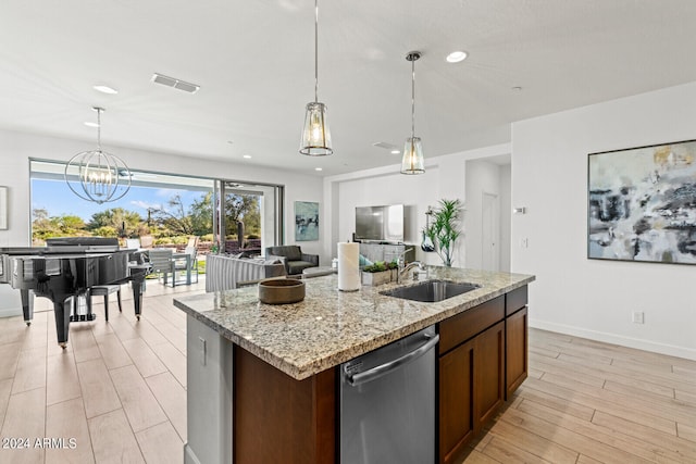 kitchen featuring light stone countertops, stainless steel dishwasher, a center island with sink, pendant lighting, and sink