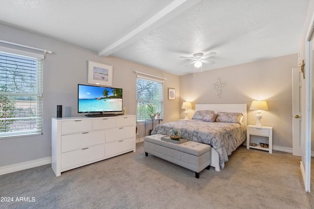 bedroom with ceiling fan, beamed ceiling, and light colored carpet