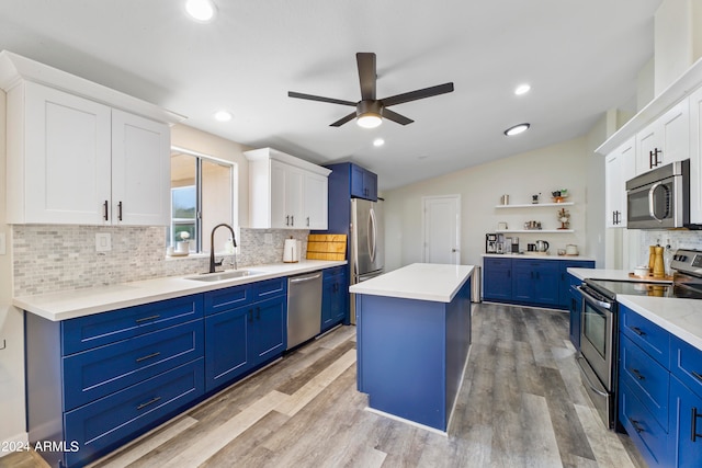 kitchen with appliances with stainless steel finishes, a center island, ceiling fan, sink, and white cabinetry