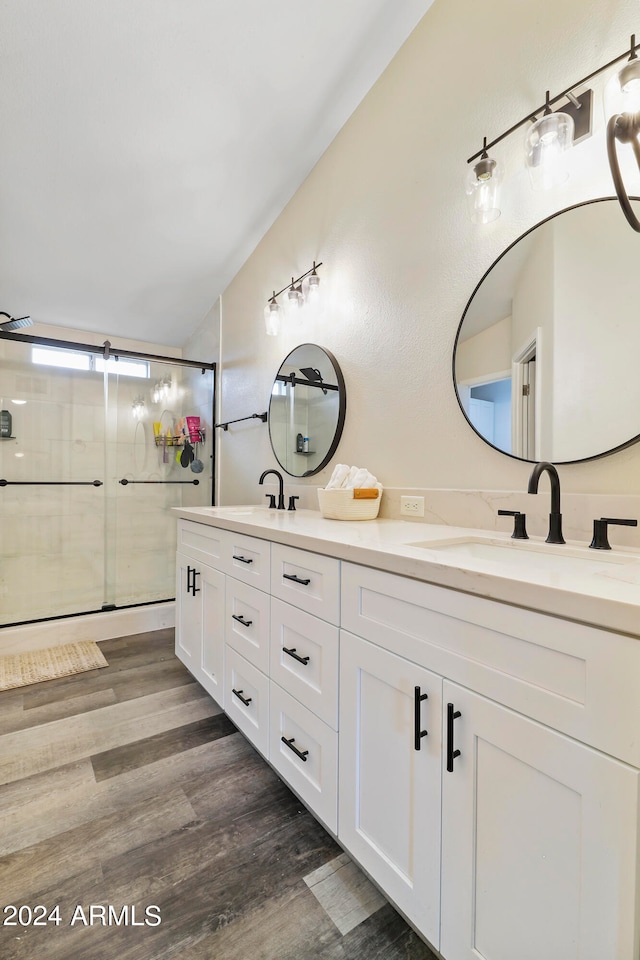 bathroom featuring walk in shower, wood-type flooring, and dual bowl vanity