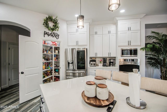 kitchen featuring stainless steel appliances, wood finished floors, light countertops, and white cabinetry