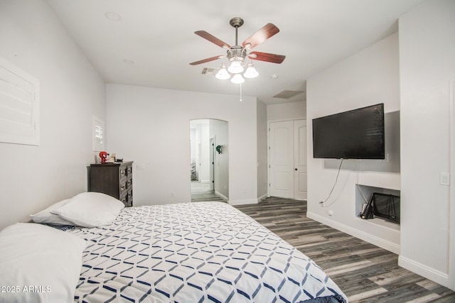 bedroom featuring arched walkways, visible vents, ceiling fan, wood finished floors, and baseboards