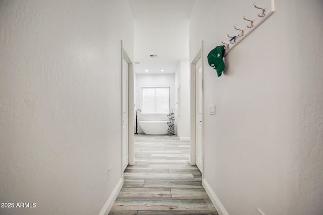 corridor featuring light wood-type flooring and baseboards