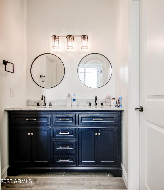 bathroom with baseboards, double vanity, a sink, and wood tiled floor