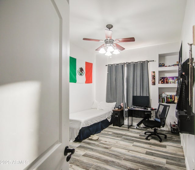 office area featuring ceiling fan, built in shelves, and wood finished floors