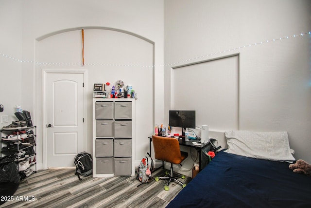 bedroom featuring arched walkways and wood finished floors