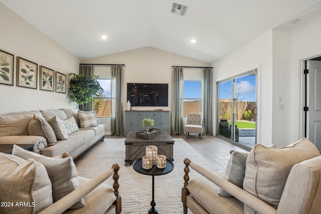 living room with lofted ceiling, light wood-type flooring, and a healthy amount of sunlight