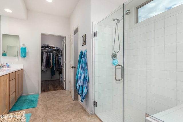 bathroom featuring a shower with door, vanity, and tile patterned flooring