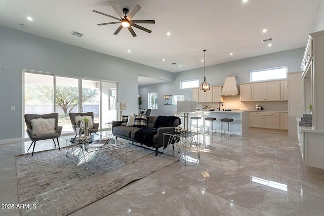 living room featuring ceiling fan, a towering ceiling, and a wealth of natural light