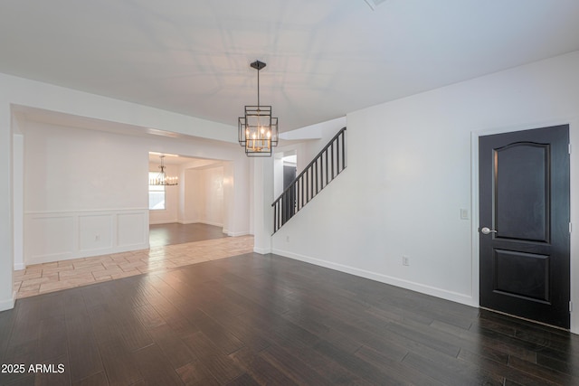 spare room with dark hardwood / wood-style flooring and an inviting chandelier