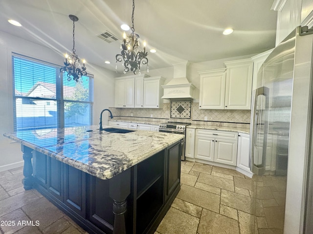 kitchen with stainless steel stove, premium range hood, light stone counters, white cabinetry, and an inviting chandelier