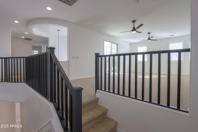 stairway featuring carpet, ceiling fan, and a healthy amount of sunlight