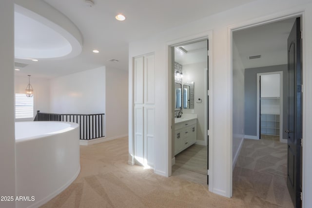 hall featuring sink and light carpet