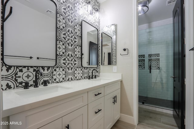 bathroom featuring a shower with door, vanity, and tasteful backsplash