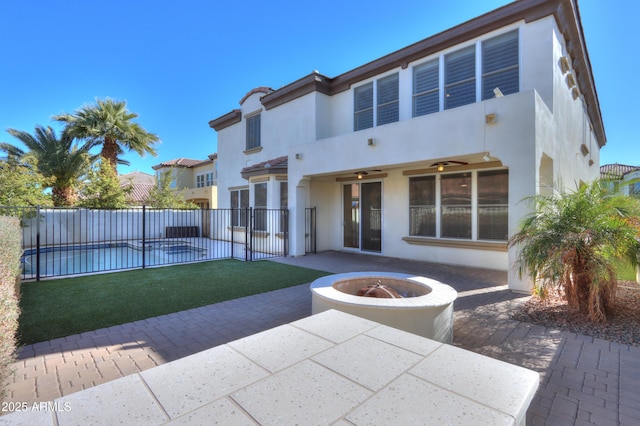 rear view of property featuring a lawn, a fire pit, ceiling fan, and a patio