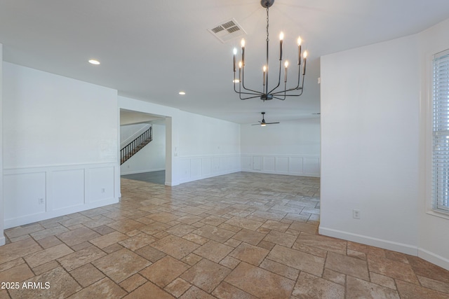 unfurnished dining area featuring ceiling fan with notable chandelier