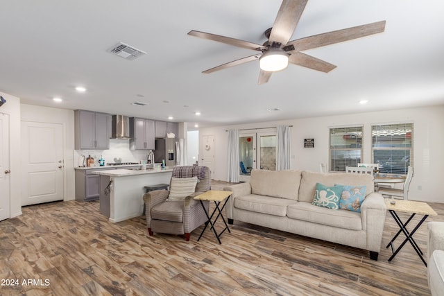 living room featuring sink, ceiling fan, and light wood-type flooring