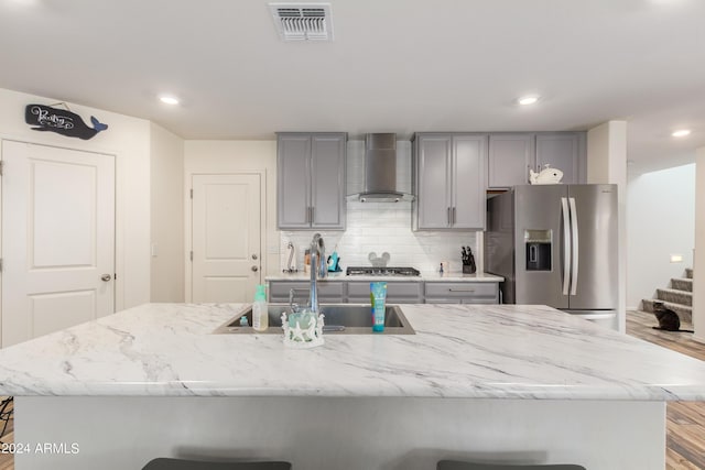 kitchen featuring sink, a breakfast bar area, wall chimney exhaust hood, and appliances with stainless steel finishes